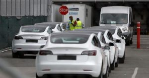 Работници се разхождат сред редица електрически превозни средства Tesla Model 3 в основната фабрика за превозни средства на Tesla във Фремонт, Калифорния, САЩ.